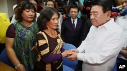 After arriving from the Philippines, Amadeo Perez, chairman of the Manila Economic and Culture Office (MECO) in Taiwan, right, apologizes to the family of a Taiwanese fisherman killed by Filipino coast guard officers in Pingtung, southern Taiwan, Aug. 8, 