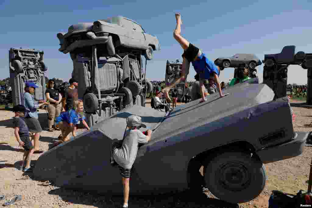 Children play on buried cars as people watch the solar eclipse at Carhenge in Alliance, Nebraska, Aug. 21, 2017.