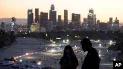 Visitantes con mascarilla observan un sitio de vacunación en el Estadio Dodger, de Los Ángeles, el viernes 15 de enero de 2021.