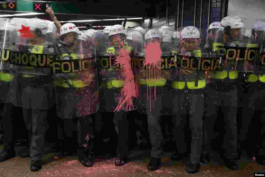 Riot police officers are seen with their shields stained with paint thrown by demonstrators, who are prevented from jumping over turnstiles, after a protest against fare hikes for city buses in Sao Paulo, Brazil, Jan. 7, 2020.