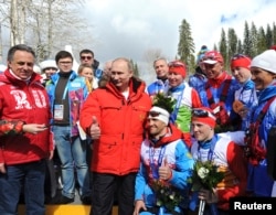 FILE - Russian President Vladimir Putin (C) poses for a picture with Russian athletes who won the cross-country skiing open relay at the 2014 Sochi Winter Paralympic Games, March 15, 2014.