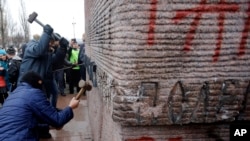 Մարդիկ քանդում են Կիևում ՊԱԿ-ի ծառայողներին նվիրված հուշարձանի վրա պատկերված տառերը, 23 փետրվարի 2014թ.