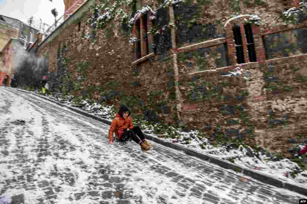 A young man slides on a snow-covered street in the Balat District of Istanbul, Turkey.