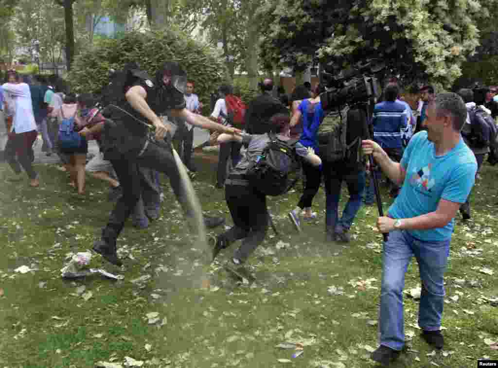 A Turkish riot policeman uses tear gas as people protest against the destruction of trees in a park brought about by a pedestrian project, in Taksim Square in central Istanbul, Turkey. 