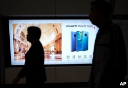 People walk past an advertisement for Huawei at a subway station in Hong Kong, Dec. 5, 2018.