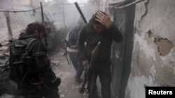 A Syrian rebel grabs his head as the smoke subsides, during fighting between the two sides in the Ain Tarma neighborhood of Damascus. Jan. 13, 2013