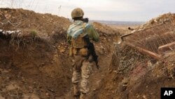 A Ukrainian soldier holds a cat and walks in a trench on the line of separation from pro-Russian rebels near Debaltsevo, Donetsk region, Ukraine, Dec 3, 2021.