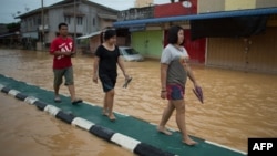 Local residents walk on a road divider to avoid floodwaters in Kota Bahru, Dec. 28, 2014. 