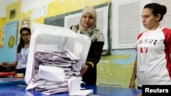 Petugas di Tunis menumpahkan kertas suara menyusul pemilu di Tunisia (26/10). (Reuters/Anis Mili)