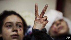 In this Saturday, March 10, 2012 file photo, Hana, 12, flashes the victory sign next to her sister Eva, 13, as they recover from severe injuries after the Syrian Army shelled their house in Idlib, north Syria. Their father and two siblings were killed aft