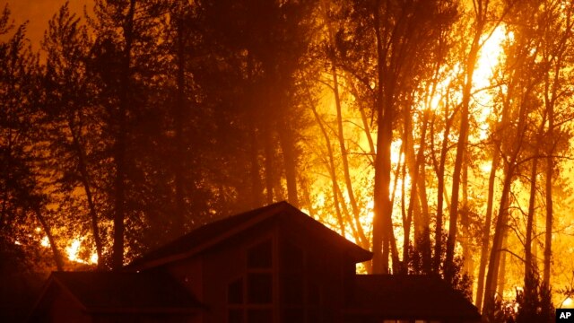 Un incendio forestal arde detrás de una casa en Twisp, estado de Washington, el miércoles, 19 de agosto de 2015.