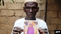FILE - Sani Garba, 55, holds a picture of his then 14-year-old daughter-in-law Wasila Tasi'u, in Unguwar Yansoro, 63 kilometers north of Kano, Nigeria. Charges were dropped against the girl, now 14, who was accused of killing her 35-year-old husband. 