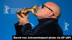 Gianfranco Rosi, directeur de 'Fuocomare', embrasse l'Ours d'or du meilleur film lors de la cérémonie de remise des prix 2016 au Festival de Berlin Berlinale le samedi 20 février 2016 à Berlin. (Bernd von Jutrczenka / pool photo via AP)