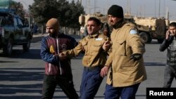 A wounded security guard receives help after being rescued from Kabul's Intercontinental Hotel during an attack by gunmen in Kabul, Afghanistan, Jan. 21, 2018.