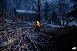 Streets department workers David Boardly, left, and James Ockimey clear a downed tree during a winter storm, March 2, 2018, in Marple Township, Pa.