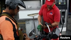 A gas station worker pumps gas into a motorbike at a gas station of the Venezuelan state-owned oil company PDVSA in San Antonio, Venezuela, Sept. 4, 2018.