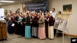 A group photo of the seventeen freed hostages is seen next to the podium as Christian Aid Ministries staff members close a news conference by singing "Nearer My God to Thee" at Christian Aid Ministries home office in Berlin, Ohio, Dec. 20, 2021. 