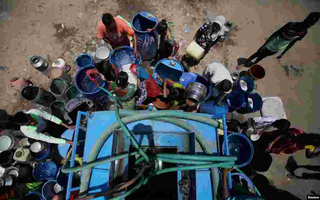인도&nbsp;아마다바드에서 시민들이 시에서 제공한 물탱크에 호스를 연결해 용기에 물을 채우고 있다.&nbsp;