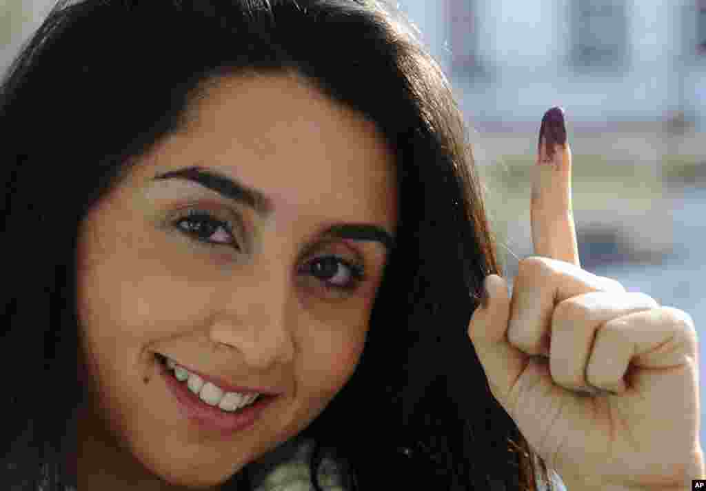 Tunisian voter Dina Ghlisse, 19, displays her finger with the indelible ink mark after voting in La Marsa, on the outskirts of Tunis, Tunisia, Sunday, Dec, 21, 2014.