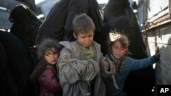 Women and children exit the back of a truck as they arrive at a U.S.-backed Syrian Democratic Forces (SDF) screening area after being evacuated out of the last territory held by Islamic State militants, in the desert outside Baghuz, Syria, March 1, 2019. 