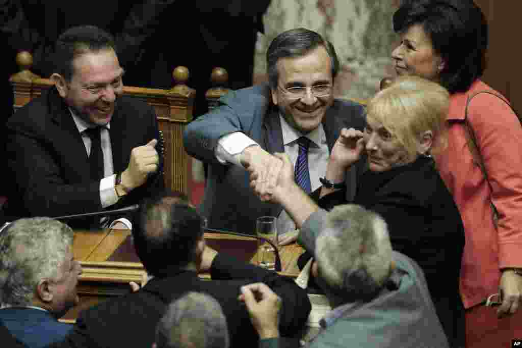 Greek Finance Minister Yannis Stournaras, left, and Greek Prime minister Antonis Samaras, second left, are congratulated by lawmakers after a parliament vote in Athens, July 18, 2013.