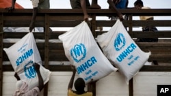 FILE - Workers unload sacks of UNHCR aid supplies at the Al Adala settlement for internally displaced people in Mogadishu, Somalia, Aug.13, 20.
