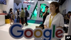 Visitors talk to staff members at a Google stand during the Global Mobile Internet Conference (GMIC) in Beijing, April 28, 2017. Google's search engine and email service remains blocked in mainland China but Chinese companies make use of its ad services to reach a global audience.