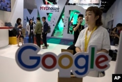 FILE - Visitors talk to staff members at a Google stand during the Global Mobile Internet Conference (GMIC) in Beijing, China, Apr. 28, 2017.