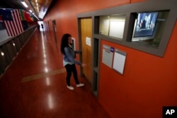 Chelsea Barber, a junior communications major at Kean University in Union, N.J., walks into her journalism class where a presentation about fake news is shown on a screen, seen through a window, Jan. 20, 2017.