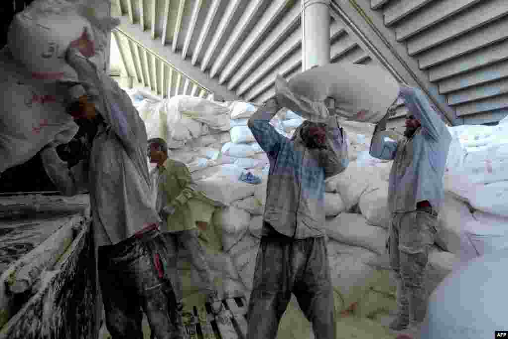 Workers load bags of flour donated by Iraq into trucks to remove them from their current storage under the Beirut Sports City stadium bleachers, in the Lebanese capital.