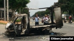 Passersby photograph a burned out vehicle after angry mobs burned and looted scores of foreign-owned factories in Vietnam. Many of the protesters are workers against China's recent placement of an oil rig in disputed Southeast Asian waters, officials said.