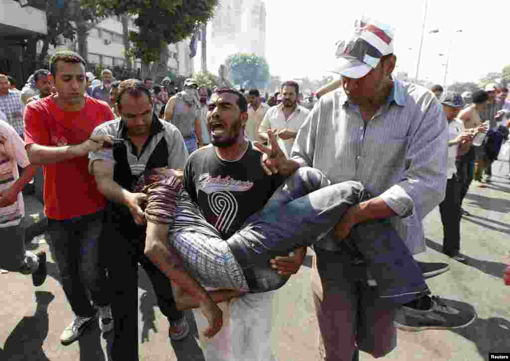 Supporters of former Egyptian President Mohamed Morsi carry an injured man during clashes outside the Republican Guard building in Cairo, July 5, 2013.&nbsp;