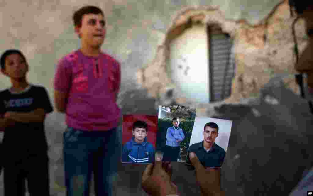 Syrian Hamzah Abu Bakri, displays portraits of his brothers who were killed last week while standing by their vegetable shop in Aleppo, Syria, September 2, 2012. 