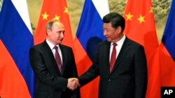 Presiden Rusia Vladimir Putin (kiri) dan Presiden China Xi Jinping berjabat tangan dalam pertemuan di Beijing, Juni 2016.