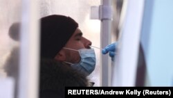 A person is tested for COVID-19 in Times Square as the Omicron coronavirus variant continues to spread in Manhattan, New York City, U.S., December 20, 2021. REUTERS/Andrew Kelly