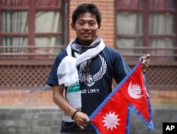 Japanese climber Nobukazu Kuriki poses with a Nepalese flag during a press conference in Kathmandu, Nepal, Sunday, Aug. 23, 2015.
