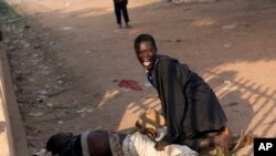 Foto yang diambil pada 23 Desember 2013 menggambarkan seorang pria di samping temannya yang terluka parah dalam kekerasan di Sudan Selatan.