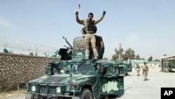 An Afghan soldier raises his hands as a victory sign, in Kunduz city, Oct. 2, 2015. 