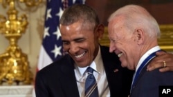 FILE - President Barack Obama laughs with Vice President Joe Biden during a ceremony in the State Dining Room of the White House in Washington, Jan. 12, 2017.