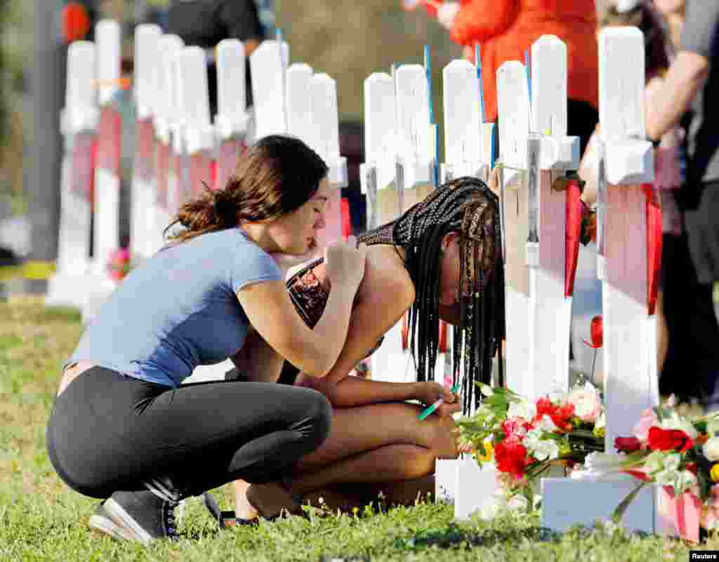 A senior at Marjory Stoneman Douglas High School weeps in front of a cross and Star of David for shooting victim Meadow Pollack while a fellow classmate consoles her at a memorial by the school in Parkland, Florida, Feb. 18, 2018.