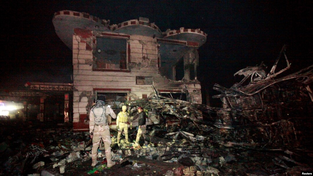 Iraqi security forces inspect the site of a suicide truck bomb attack, at a gas station in the city of Hilla, south of Baghdad, Iraq, Nov. 24, 2016.
