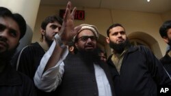 FILE - Hafiz Saeed, head of the Pakistan's Jamaat-ud-Dawa group, waves to supporters in Lahore, Pakistan, Nov. 24, 2017. Pakistan has amended its anti-terrorism law that authorizes the government to blacklist charities linked Saeed, who has been wanted since 2012 for his role in planning the 2008 Mumbai terror attack. 