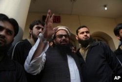 FILE - Hafiz Saeed, head of the Pakistan's Jamaat-ud-Dawa group waves to supporters at a mosque in Lahore, Pakistan, Nov. 24, 2017.