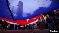 FILE - Supporters rallying for the nation’s peace agreement with FARC hold a giant flag during a march in Bogota, Colombia, Nov.15, 2016. 