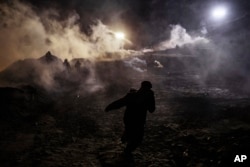 Migrants run as tear gas is thrown by U.S. Border Protection officers to the Mexican side of the border fence after they climbed the fence to get to San Diego, California, from Tijuana, Mexico, Jan. 1, 2019.