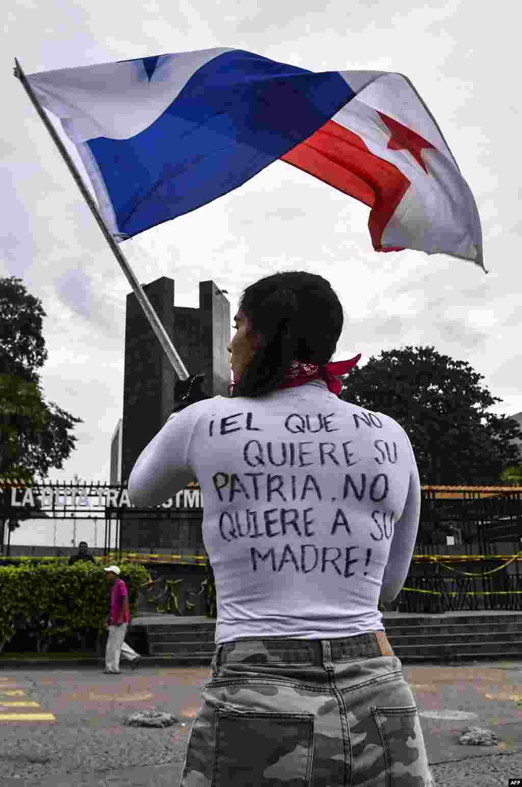 Un manifestante lleva una camisa que dice "el que no ama a su país, no ama a su madre" y agita una bandera durante los enfrentamientos con la policía antidisturbios. 