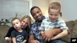 Damon Brown sits with his wife, Bethany, as they hold their sons Theo, 3, left, and Julian, 5, at their home in Seattle. Damon Brown found a kidney on Facebook after telling his story on a special page the Seattle dad created under the name, “Damon Kidney