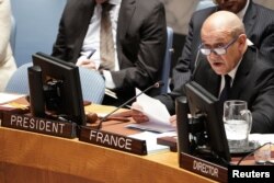 French Foreign Minister Jean-Yves Le Drian speaks with an aide at the United Nations during a meeting about combatting the financing of terrorism in New York, March 28, 2019.