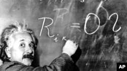FILE - Dr. Albert Einstein writes out an equation for the density of the Milky Way. The satellite launched Monday will test the concept that in a vacuum, all bodies fall at the same speed -- an idea on which Einstein based the theory of general relativity that made him famous.