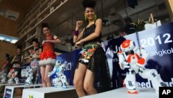 FILE - Humanoid robots called Nao, developed by a French company, Aldebaran Robotics, dance along with models to mark the opening of a press conference of the Manufacturing Expo in Bangkok,